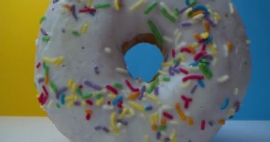 Süper makro yakın plan renkli şekerli tatlı çörekler. - Harika. Kamera donuttaki delikten uçarak geçer, iki kekin içinden geçer ve sarı arka planda duran diğer çöreğe ulaşır..