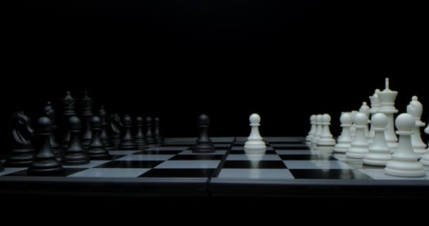 Game of chess. Filmed in a dark key. White moves with a pawn. Super-macro photography of a chessboard with chess, camera travel on a slider from white pieces to black ones. — Stock Video