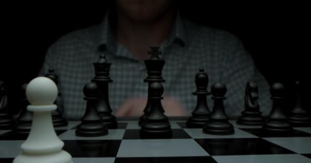 Schachspiel. Gedreht in einem dunklen Schlüssel. Weiß zieht mit einem Bauern. Super-Makro-Fotografie eines Schachbretts mit Schach, Kamerafahrt auf einem Schieberegler von weißen zu schwarzen Figuren. — Stockvideo