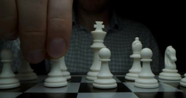 Satranç oyunu. Kara bir anahtarla çekilmiş. Piyonlu beyaz hareketler. Satrançlı bir satranç tahtasının süper makro fotoğrafçılığı, kamera beyaz parçalardan siyah olanlara kaydırma makinesiyle seyahat ediyor..