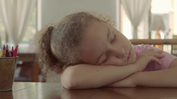 Close-up face of a little girl sleeping baby on her side in her arms. 8 year old girl sleeping sweetly at the table after drawing lesson. 4k footage of a sleeping child who fell asleep after drawing. — Stock Video