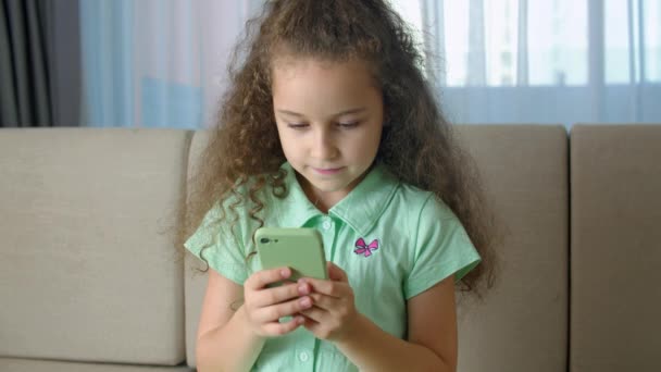 Honing kind met behulp van smartphone, kind surfen op het internet, praten op de smartphone, maakt gebruik van video-communicatie thuis op de telefoon. Portret schattig kind meisje Schooljongen houdt een telefoon. — Stockvideo