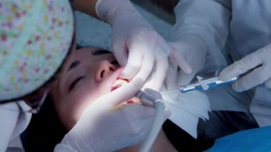 Bir dişçi genç kadın hastasına sözlü muayene yapıyor. Ortodontiste bir randevu. Geçici bir dolguyu kalıcı bir dolguyla değiştirmek. Parlatma.