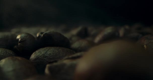 Detailní záběr pražených kávových zrn, natočený v temném klíči, kouř vycházející z pražení kávových zrn. Koncept aromatických kávových zrn. — Stock video