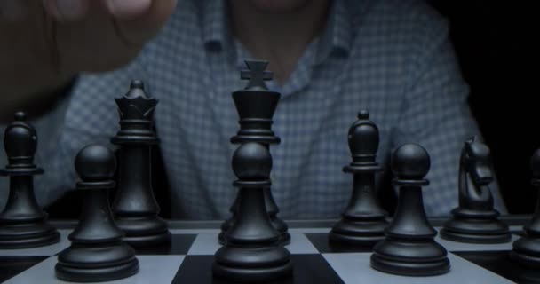 Game of chess. Filmed in a dark key. White moves with a pawn. Super-macro photography of a chessboard with chess, camera travel on a slider from white pieces to black ones. — Stock Video