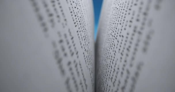 Het boek is geopend om te lezen. Man opent een boek om te lezen, op een blauwe achtergrond close-up van pagina 's in een boek. Concept super macro shot, close-up van pagina 's in een boek. — Stockvideo