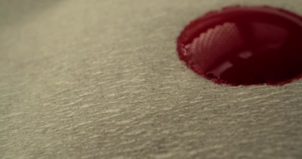 Rood bloed concept. Bloeddruppels druppelen op een papieren servet, bloed verspreidt zich over het servet, macro shot.. — Stockvideo