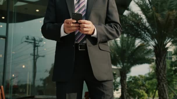 4k Mężczyzna czyta wiadomości telefoniczne lub pobiera aplikację na telefon komórkowy.Uśmiechnięty biznesmen w średnim wieku w luksusowej odzieży w dzielnicy finansowej w metropolii za pomocą telefonu komórkowego do smsowania — Wideo stockowe