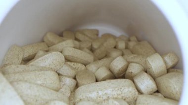 Reçeteli ilaç şişesi bej haplarla dolu, kameralı makro mercekli kaydırma makinesinde yavaş çekim.