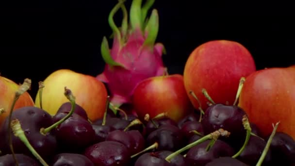 Съемка в темном ключе спелые вишни, яблоки, фрукты дракона на черном фоне, путешествие на слайдере через фрукты на столе. — стоковое видео