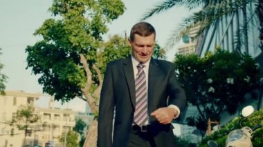 Başarılı orta yaşlı iş adamı şehir merkezinde lüks giysiler içinde bir iş toplantısına koşuyor, ortaklarıyla bir iş görüşmesini yakalamak için saatine bakıyor, teknoloji, iletişim, başarı.