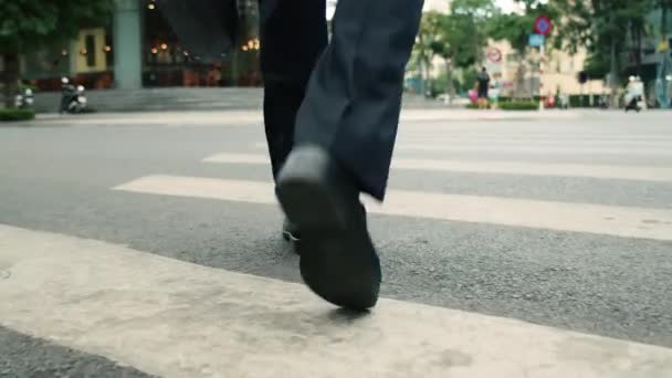 Close up rear view of a hurry aucasian middle aged business man in leather shoes and suit on the way to the office building,businessman in a suit crosses the road on a zebra crossing, man gets to work — Stockvideo