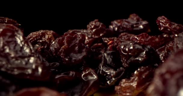 Una macro de uvas secas con un primer plano de pasas maduras yace sobre una mesa sobre un fondo negro. Macro primer plano de pasas de uva. Ángulo interesante, material de archivo. — Vídeo de stock