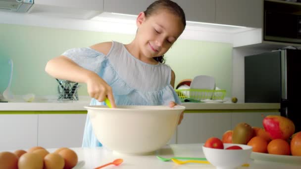 Happy cute bambina di otto anni sta cucinando in cucina, alcuni figlia sta montando una miscela con la farina in cucina, una bambina sta facendo la pasta per fare frittelle o torte. — Video Stock