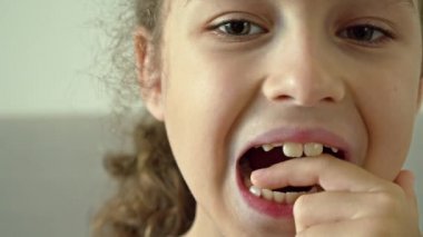 Yüzünde gülümseme olan bir çocuğun portresi süt dişini gevşetiyor. 8-9 yaşlarında şirin bir kız süt dişlerini kaybediyor. Yapraklı dişlerin dökülmesi, kalıcı dişlerin değiştirilmesi. Çocuklar.