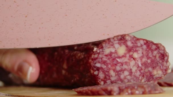 Sausage slicing, Close view woman hands cutting sausage with sharp knife. Hand slicing salami sausage on wooden chopping board. Footage of slicing smoked pork — Stock Video