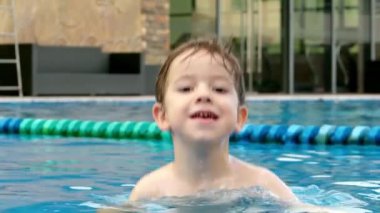 Gözlüklü neşeli çocuk havuzda banyo yapıyor. Havuzda yüzme gözlüklü şirin bir çocuk, havuza atlayan bir çocuk..