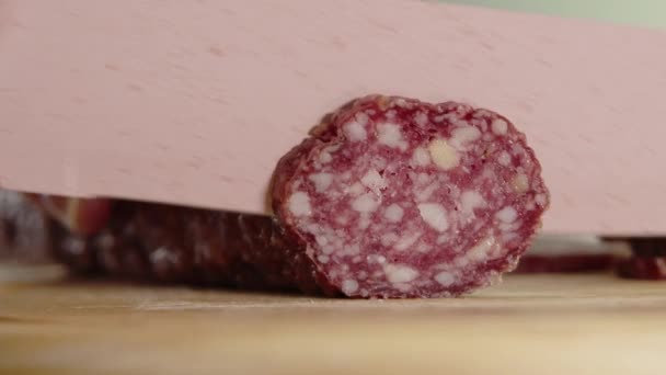 Sausage slicing, Close view woman hands cutting sausage with sharp knife. Hand slicing salami sausage on wooden chopping board. Footage of slicing smoked pork — Stock Video