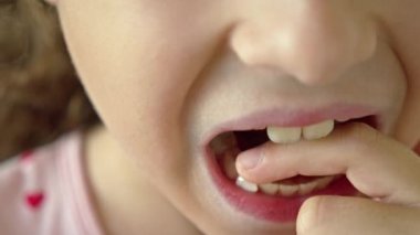 Yüzünde gülümseme olan bir çocuğun portresi süt dişini gevşetiyor. 8-9 yaşlarında şirin bir kız süt dişlerini kaybediyor. Yapraklı dişlerin dökülmesi, kalıcı dişlerin değiştirilmesi. Çocuklar.