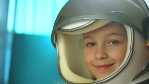 Çocuk evde bir astronotta oynuyor, 8-9 yaşlarında oyuncak kasklı komik bir kızın portresi, kameraya bakan gülümseyen bir çocuk, yakın çekim, uzaya seyahat eden bir pilot. Mutlu bir çocukluk kavramı. — Stok video