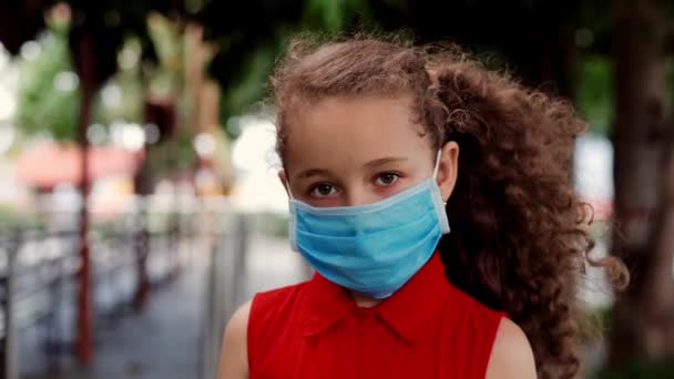 Παιδί ένα μικρό κορίτσι, 7-8 ετών, στέκεται στο δρόμο φορώντας προστατευτικές μάσκες κατά της επιδημίας Covid-19. Υγεία και ασφάλεια ζωής, Covid-19, προστασία από ιούς, πανδημία στον κόσμο — Αρχείο Βίντεο