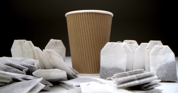 Супер крупним планом набір чайних пакетів на білому столі на чорному тлі коричневий паперовий чайний стаканчик. . — стокове відео