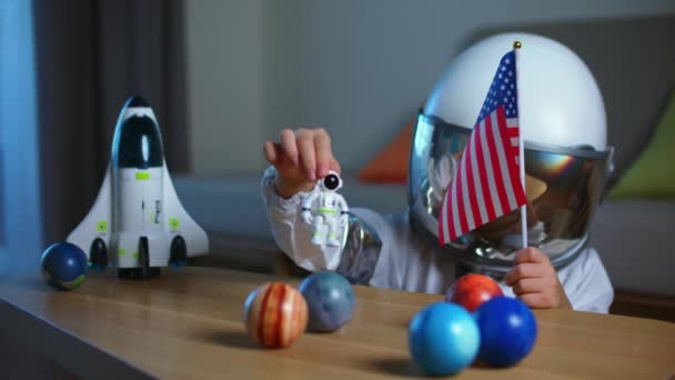 Criança brinca em casa em um astronauta, retrato engraçado de uma menina de 8-9 anos de idade em um terno espacial de brinquedo, uma criança sorridente, lança um foguete espacial, close-up, um piloto viajando no espaço. Infância feliz — Vídeo de Stock