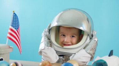 Gülümseyen bir çocuk elini sallar, kameraya bakar, yakın çekim yapar, uzaya uçar. Çocuk evde bir astronotla oynar. 5-6 yaşlarında oyuncak bir çocuğun komik portresi. Mutlu çocukluk.