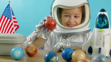 Elinde Mars 'ın kırmızı bir uzay roketini tutan gülümseyen çocuk, yakın plan, uzaya seyahat eden pilot. Çocuk evinde bir astronotta oynuyor, 8-9 yaşındaki küçük bir kızın oyuncak içinde komik bir portresi.