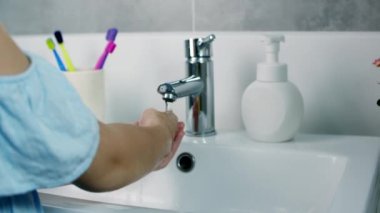 Bir çocuk ellerini sabunla yıkıyor, küçük kız elleri virüs ve bakterilerin yayılmasını önlemek için yıkıyor. Sağlık, temel ev hijyeni..