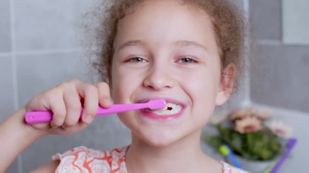 Портрет счастливая милая молодая девушка подросток чистить teethin утром в ванной комнате и улыбаясь. Ежедневная медицинская помощь детям. Кавказский ребенок с белым зубом смотрит на изолированное зеркало дома. — стоковое видео
