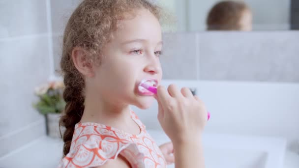 Portret gelukkig schattig jong tienermeisje borstelen tanden in de ochtend in de badkamer en glimlachen. Kinderen dagelijkse gezondheidszorg routine. blank kind met witte tand kijken naar spiegel geïsoleerd thuis. — Stockvideo