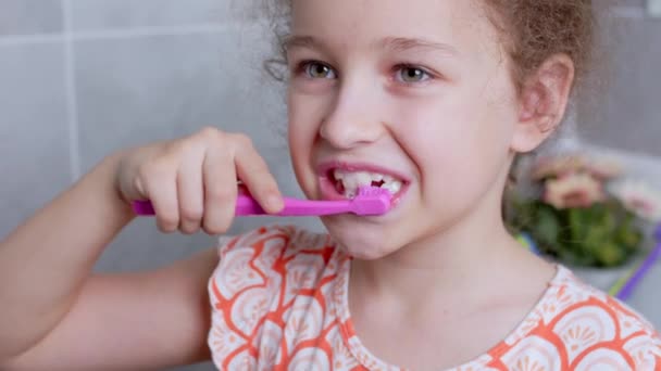 Portret gelukkig schattig jong tienermeisje borstelen tanden in de ochtend in de badkamer en glimlachen. Kinderen dagelijkse gezondheidszorg routine. blank kind met witte tand kijken naar spiegel geïsoleerd thuis. — Stockvideo