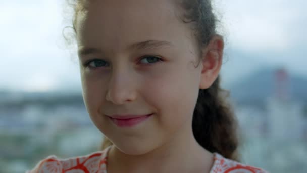 Ritratto Bambina che guarda la macchina fotografica in piedi in strada in città il giorno d'estate. Giovane felice pensiero curiosità bambino guardando fotocamera primo piano all'aperto. Occhi viso serio contemplativo bambino. — Video Stock