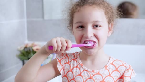 Retrato feliz linda adolescente joven cepillarse los dientespor la mañana en el baño y sonriendo. Rutina diaria de salud infantil. Niño caucásico con diente blanco mirando el espejo aislado en casa. — Vídeo de stock