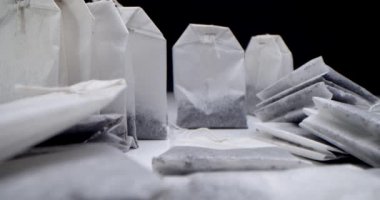 Siyah arka planda beyaz bir masanın üzerinde çay poşetleri var. Sabah çayı yapıyorum. Çay klipsi için makro atış aşçılık ve aşçılık projeleri için uygundur.