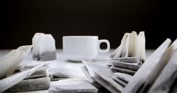 Super close-up set of tea bags on a white table on a black background is a white cup of tea.Making morning tea.This tea clip is suitable for culinary and culinary projects.Tea bag in a white cup of — Stock Video