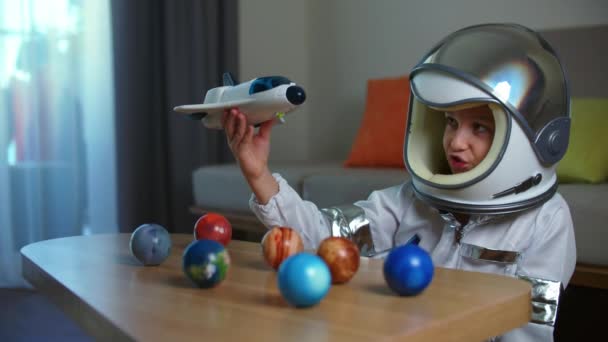 宇宙飛行士の家で遊ぶ子供、おもちゃの宇宙服の女の子8-9歳の面白い肖像画、笑顔の子供は、宇宙ロケット、クローズアップ、宇宙を旅するパイロットを起動します。幸せな子供時代 — ストック動画