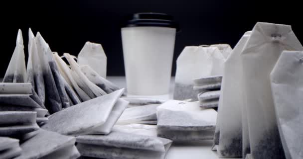 Tea bag in a white cup of tea.Super close-up set of tea bags on a white table on a black background and a white paper tea cup. — Stock Video