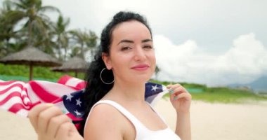 Vatanseverlik, bağımsızlık günü ve tatil konsepti. Yaz mevsiminde ulusal Amerikan bayrağıyla mayolu mutlu bir genç kadın..