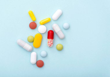 Tıbbi bileşim. Mavi arka planda bazı renkli haplar, üst manzara. Sarı, mavi, yeşil, kırmızı, beyaz kapsüller, ilaçlar.