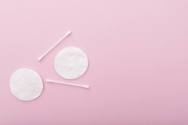 Pembe zemin üzerinde pamuk çubuklar ile pamuk pedler, metin için boşluk ile uzanır