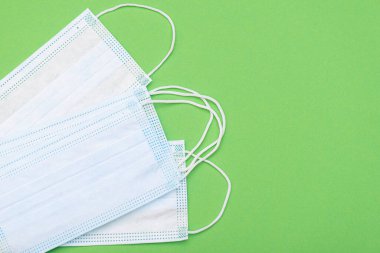 Yeşil arka planda koruyucu tıbbi maskeler, üst görüş, tıbbi tema