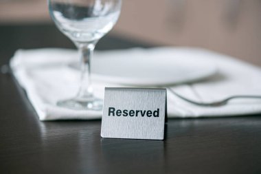 Beyaz masa örtüsü ve bir kafe veya restoranda şarap kadehinin önündeki ahşap masanın üzerine ayrılmış demir levha.