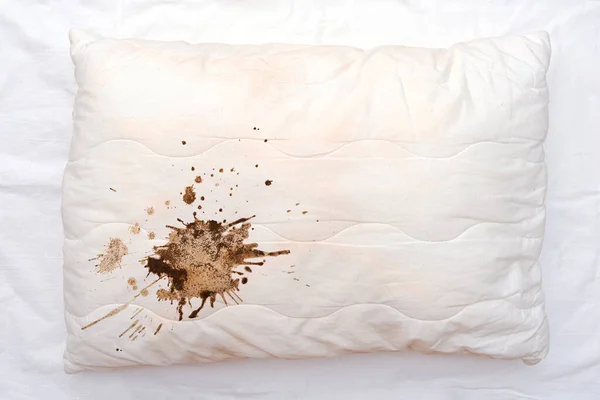 Eski beyaz yastık, buruşuk çarşafta kahve lekeleri, yatakta kirli yastık.