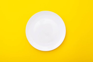 Sarı yüzeyde seramik beyaz tabak, mutfak masası, sergi, üst görünüm, metin için boşluk