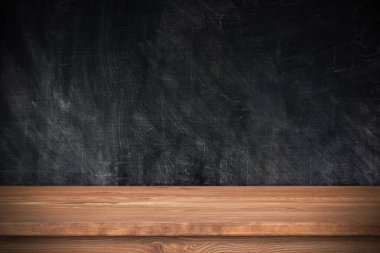 Şablon olarak siyah duvarı olan ahşap masa. Boş kahverengi masa üstü ve karatahta, metin için boşluk, nesneler 