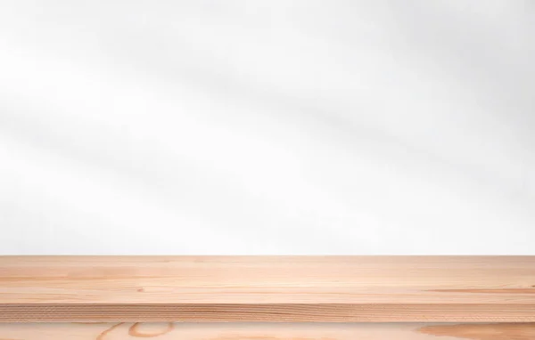 Long pine wooden table in front of wall with soft light. Empty desk, shelf or tabletop for template.