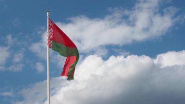 Beyaz Rusya bayrağı mavi gökyüzüne karşı rüzgarlı bir günde bayrak direğinde dalgalanıyor. Beyaz Rusya Cumhuriyeti 'nin gerçek bayrağı. Video 4k çözünürlüğü