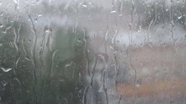 Yağmur mevsimi, şehirde şiddetli yağmur, cam yüzeyine düşen su damlaları, arka plan veya doku olarak nemli pencereler.